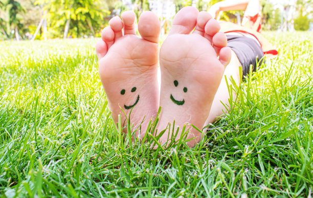 孩子们的脚上画着一幅微笑的绿色草地。有选择性的重点。图片下载