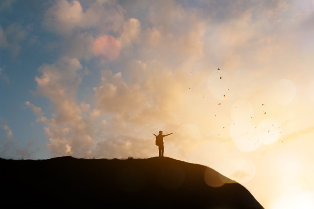 幸福的欢呼庆祝成功的女人在美丽的日落之上的云。女孩欣赏着彩色的日落，双臂高举向天空。图片下载