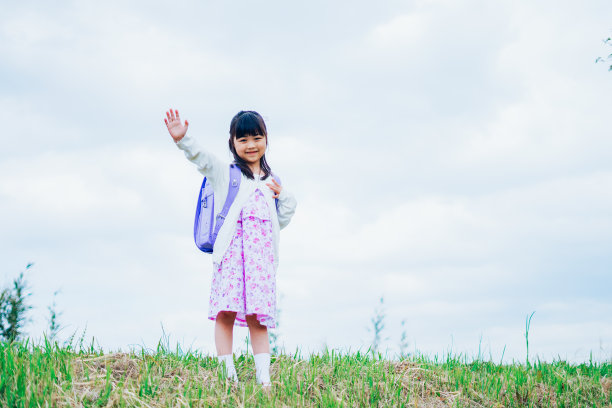 一个小女孩背着书包，挥舞着她的手图片下载