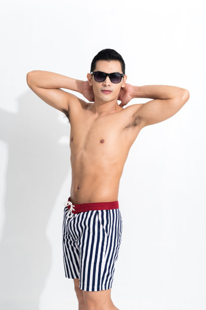 男人在条纹沙滩短裤日光浴。图片下载