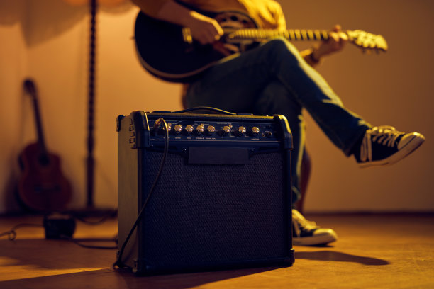 男音乐家在复古房间的扩音器上弹奏原声吉他。图片下载