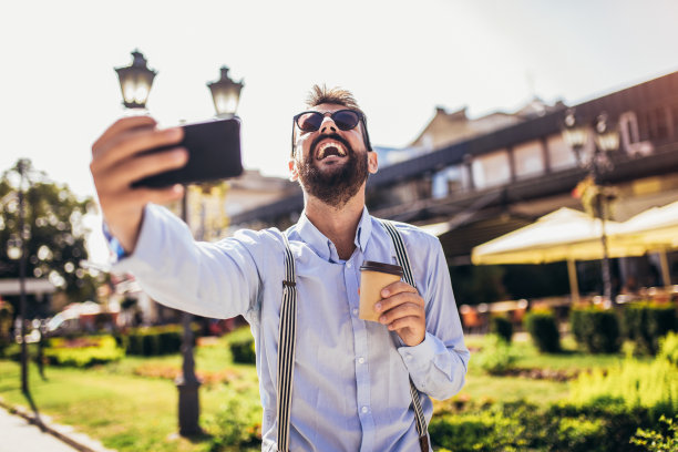 英俊的年轻人用手机自拍图片下载