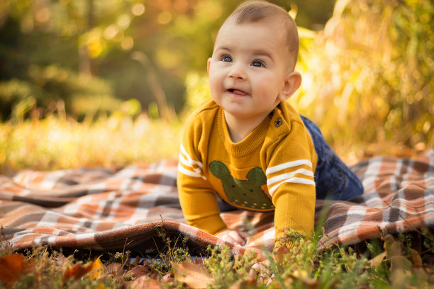 快乐的年轻妈妈和宝宝在秋天的公园里玩黄色的枫叶。秋天一家人在户外散步。秋天，小男孩和妈妈在公园里玩耍图片下载