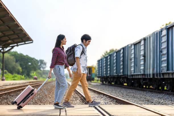 一对时尚的游客背着背包，在户外地铁站进入火车，亚洲夫妇旅游火车站复古风格的概念，在泰国图片下载