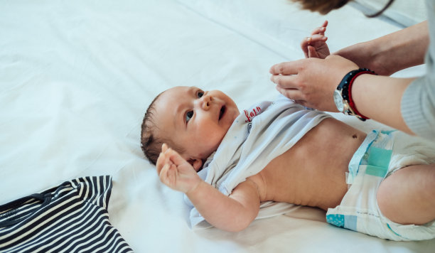 妈妈在床上给小婴儿穿衣服图片下载