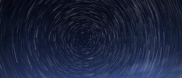 恒星轨迹是指夜晚明亮的恒星围绕着北极星在蓝色天空下的旋转图片下载