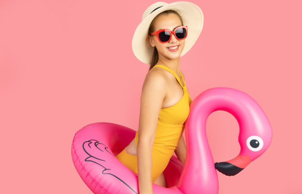 美丽，性感的亚洲女孩站在粉红色的背景。她穿着比基尼和微笑。暑假快乐旅行概念。混血女人听音乐。图片下载