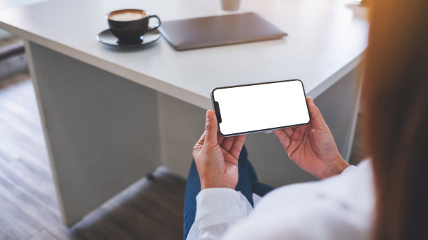 一位女士在办公室里拿着手机，手机的桌面屏幕是空白的图片下载