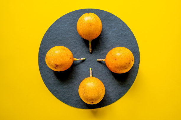 西番莲ligularis。甜granadilla。三个甜甜的百香果在黑色和黄色的背景上。图片下载