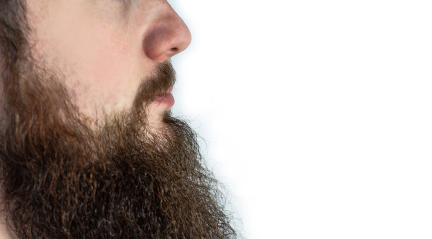 年轻的成年男子与长胡子和胡子近距离孤立在白色的背景图片下载