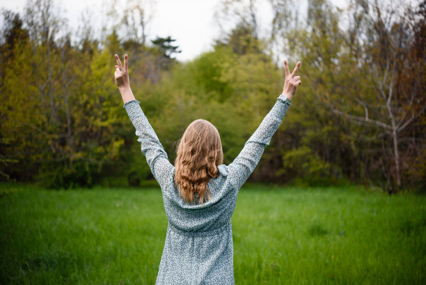 一个女人站在后面的公园里，双手举着图片下载