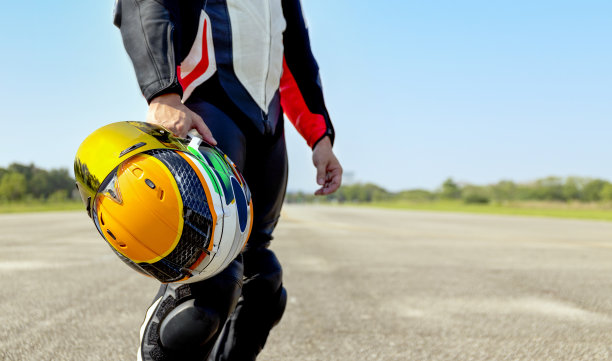 骑摩托车的人拿着他的摩托车头盔行走在道路上骑软焦点和过光在背景图片下载