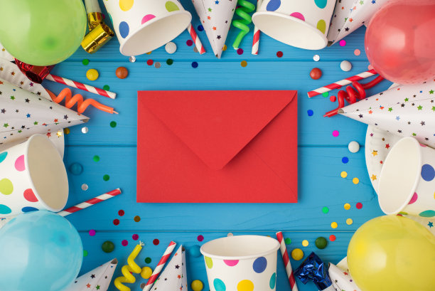 顶视图照片的生日聚会组成封闭的红色信封在中间螺旋蜡烛管道条纹草帽气球纸杯和盘子在孤立的蓝色木制桌子的背景图片下载
