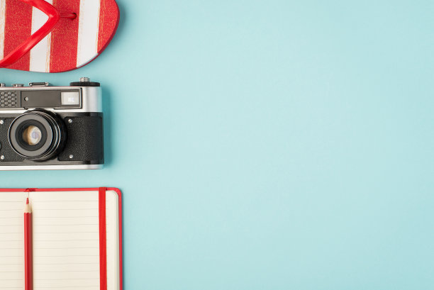 顶视图照片条纹人字拖，相机，红色铅笔和打开日记在孤立的淡蓝色背景与copyspace在右边图片下载
