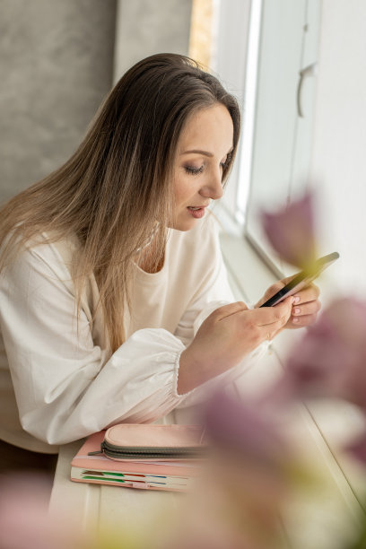 令人愉快的家庭妇女放松在现代厨房聊天使用智能手机白色烹饪室内图片下载