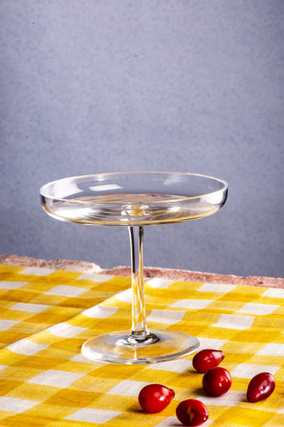 这张社交媒体美食潮流照片中，黄色桌布上放着一个玻璃杯角和一个蓝色勺子图片下载