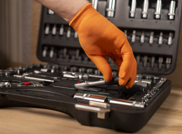 男手从工具箱中取出带有棘轮手柄的手套。工业金属工具，近距离木质背景图片下载