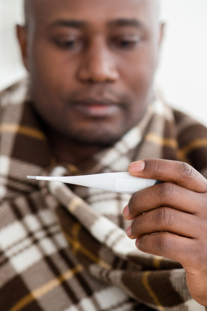 Covid-19病毒的概念。生病的非裔美国人看温度计后测量温度，作物，特写图片下载