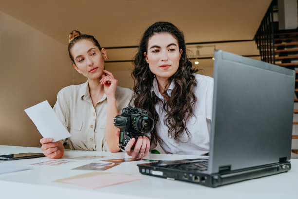 摄影师和设计师在笔记本电脑上讨论照片和打印照片图片下载