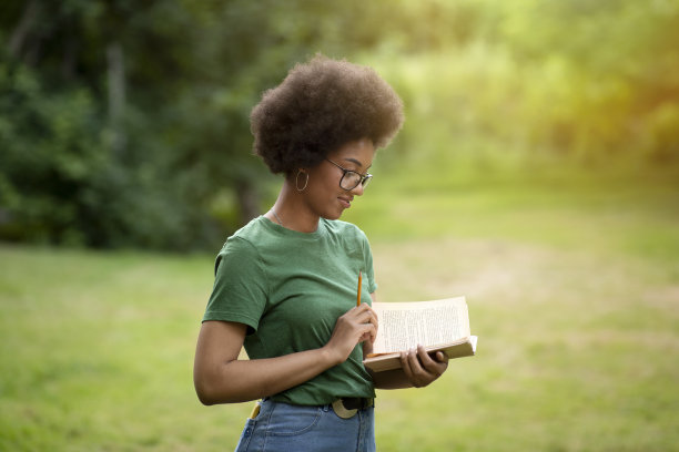 专注的黑人大学生女孩与书和铅笔在户外学习图片下载