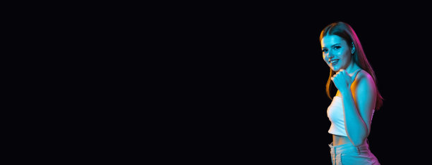 传单。年轻美丽的女孩戴着耳机，在黑暗的背景下与世隔绝。图片下载