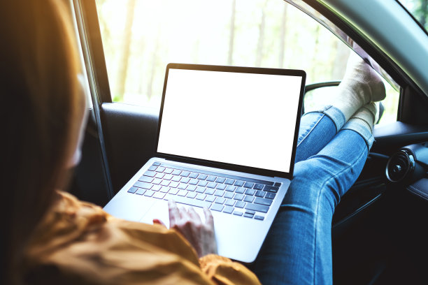 一个女人躺在车里，在笔记本电脑上用空白的桌面屏幕打字图片下载