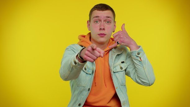 一个穿着牛仔夹克的少年看着摄像头做着手机手势好像在说嘿，你给我回电话图片下载