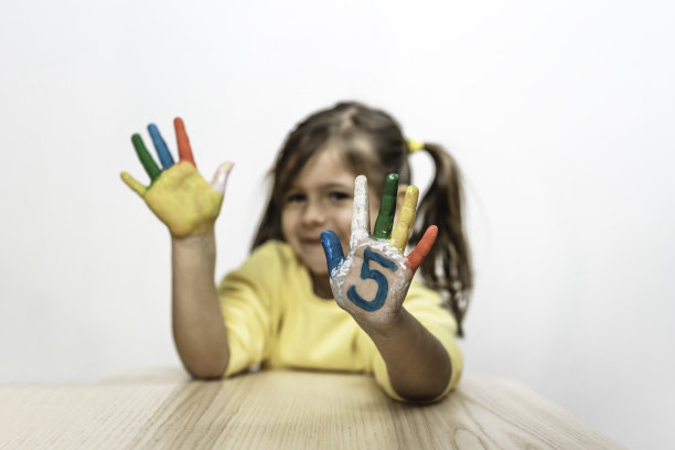 快乐的没有牙齿的小女孩与画在手上的5个数字笑和有乐趣的小女孩谁是画在她的手上的数字-数字5和童年的概念图片下载