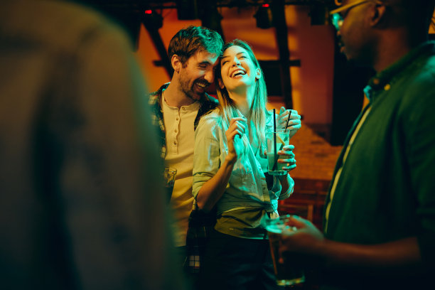 年轻的无忧无虑的夫妇有乐趣在晚上约会在酒吧。图片下载