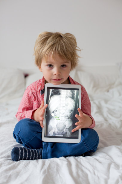 蹒跚学步的儿童，拿着儿童身体片上的x光照片和吞下的磁铁显示，儿童吞下危险物体图片下载