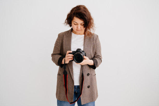 深色头发的女人在格子夹克看着照片在相机显示图片下载