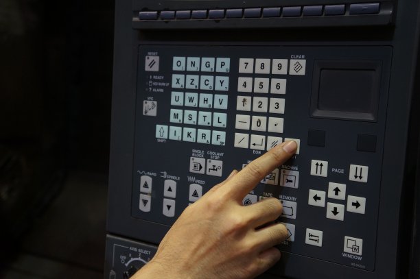 右手按下数控机床控制面板上的按钮。图片下载