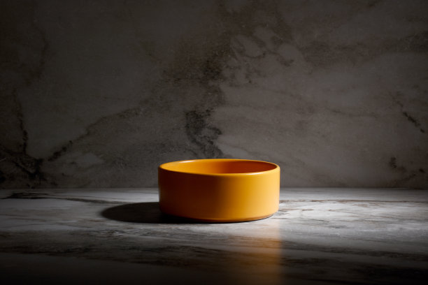 大理石背景上的橙色空陶瓷碗图片下载