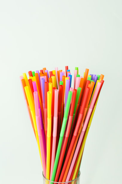 彩色鸡尾酒吸管在一个玻璃杯上的白色背景。图片下载