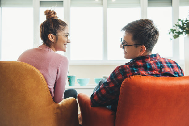 一对白人夫妇躺在扶手椅上互相微笑的背影照片图片下载