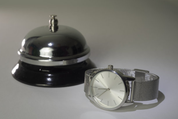 接待处的铃铛和灰白色背景上的手表。开放的时间。近距离图片下载