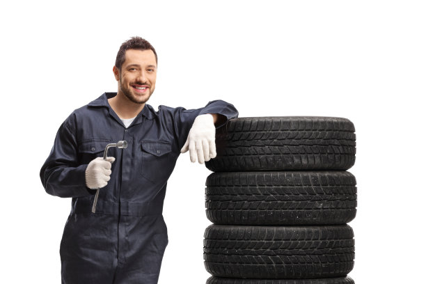 汽车修理工拿着一个扳手，靠在汽车轮胎上图片下载