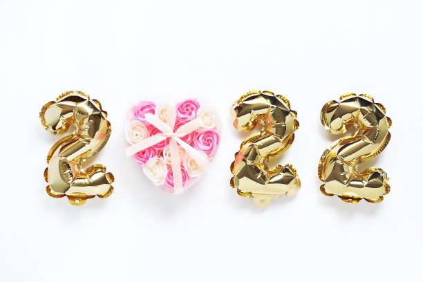 圣诞节或新年的背景。2022年，用金球做成，白色背景，化妆皂做成玫瑰心的形状。明信片或日历。新年快乐或圣诞快乐。图片下载