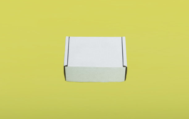 黄色背景上的白色纸板箱模型。空间的文本图片下载