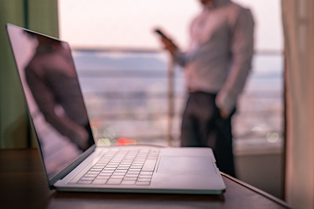 电脑的特写镜头，背景是一个模糊的年轻男子图片下载