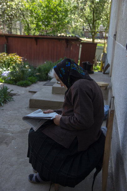 很老的老妇人坐在后院的椅子上看报纸图片下载