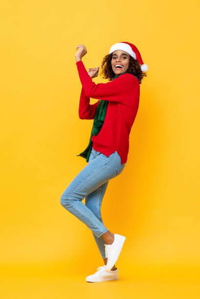 全身像的乐趣快乐的女人在圣诞节服装跳舞在孤立的黄色工作室背景图片下载