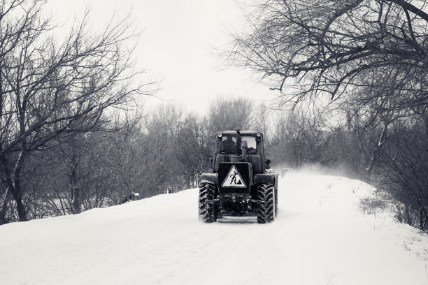 黑色和白色的旧拖拉机清除积雪覆盖的道路从积雪堵塞图片下载