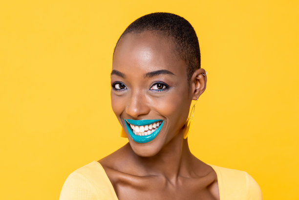 近距离的微笑年轻的非洲裔美国妇女与时尚多彩的化妆孤立在黄色工作室背景图片下载