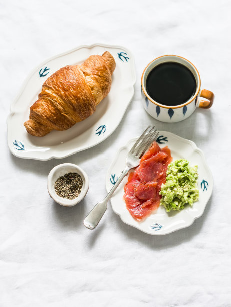 美味的早餐，早午餐-黑咖啡，鳄梨泥，烟熏鲑鱼，牛角面包在一个轻的背景，俯视图图片下载
