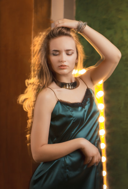 在灯光背景下摆姿势的迷人的穿着衣服的女人图片下载