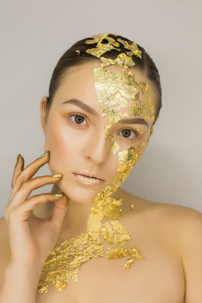 近距离拍摄的漂亮的年轻女子与创造性的化妆金箔图片下载
