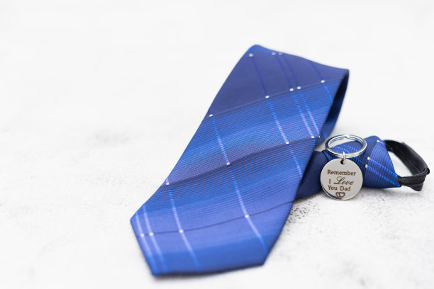 以石头为背景的父亲节的钥匙链和短蓝领带礼物场景图片下载