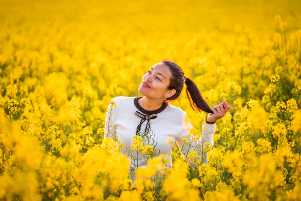 美丽可爱的拉丁姑娘站在黄色的油菜籽地里图片下载