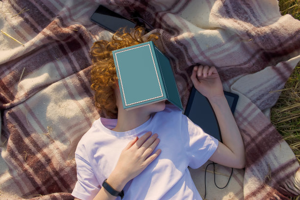 少年在户外读书。少年脸上放着一本书睡觉图片下载